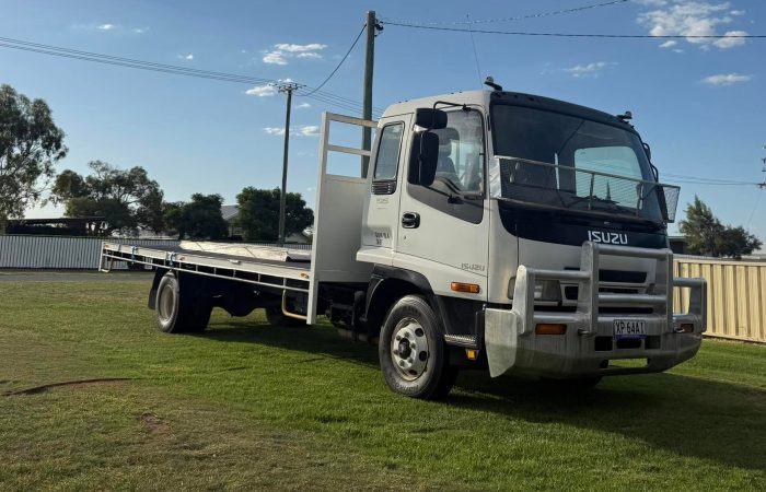 Isuzu tilt tray truck parked under a big blue sky, ready for a hay or equipment run. Built by Blocka's Rural and Earthworx near Warwick, QLD.