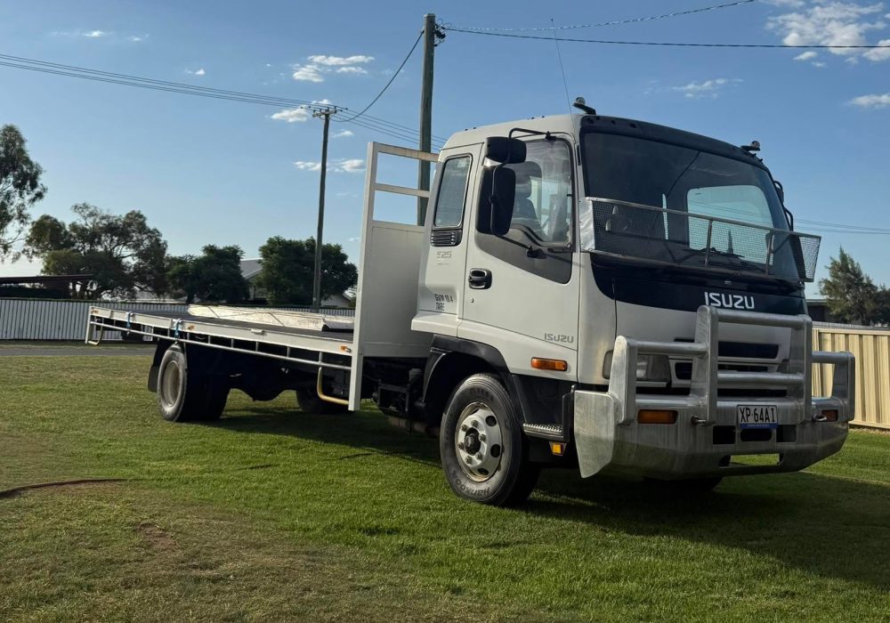 Isuzu tilt tray truck parked under a big blue sky, ready for a hay or equipment run. Built by Blocka's Rural and Earthworx near Warwick, QLD.